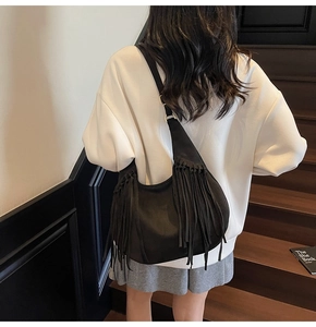 Detail of black suede hobo bag featuring long stylish fringes and adjustable strap