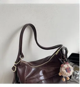 Detail of dark brown oil-wax leather shoulder bag with wide handle and cute charm