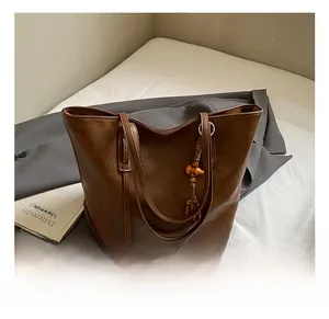 Dettaglio borsa tote marrone scuro con ciondolo in perline di legno e nappa etnica