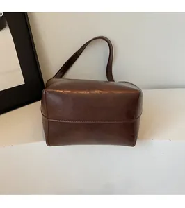 Détail du sac seau en similicuir marron foncé avec texture rétro et bandoulière fine