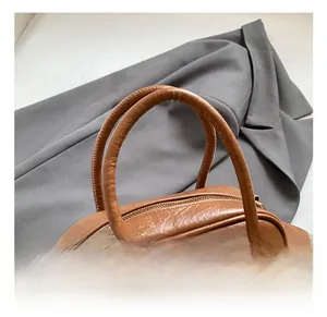 Vue détaillée du sac à main en cuir marron grainé avec doubles poignées cylindriques