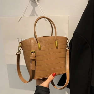 Close-up of brown crocodile texture tote bag with golden hardware and adjustable strap