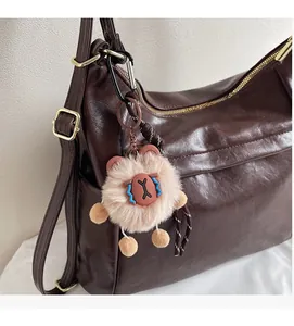 Detail of a fluffy brown animal plush charm attached to a leather bag handle