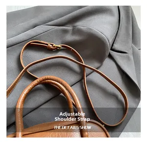 Détail d'un sac bowling en cuir marron avec bandoulière réglable et ferrures dorées
