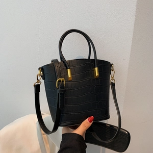 Detail of black crocodile texture bucket bag with dual round handles and gold hardware