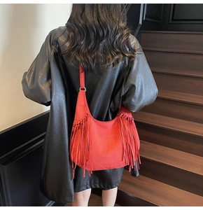 Detail of red suede tote bag with long tassels and metal rings in a bohemian style