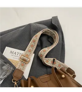 Détail d'un sac seau vintage en cuir marron avec bandoulière large brodée et colorée