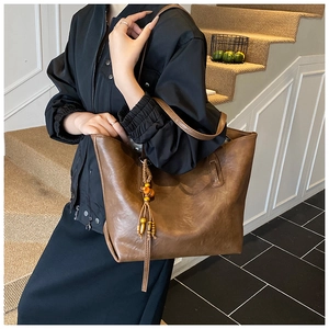 Dettaglio della borsa tote in pelle marrone con nappa in legno e finitura testurizzata