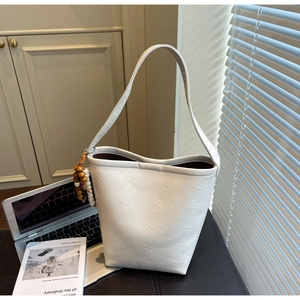 Detail of off-white marble texture bucket bag with wooden bead charm in a home setting