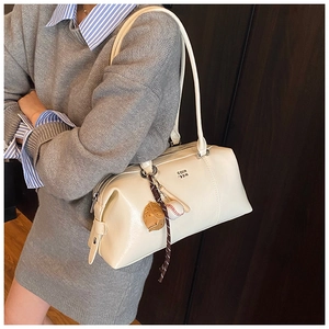 Detail of cream Boston bag featuring embossed COIN PRDN logo and baseball charm