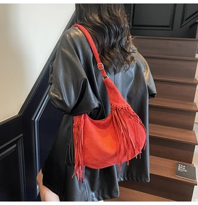 Detailed view of red suede hobo bag with long fringes and adjustable metallic buckle