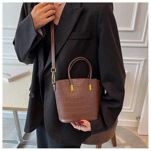 Detail of coffee brown crocodile texture handbag with gold hardware and shoulder strap