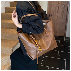 Dettaglio di una borsa tote in pelle vintage marrone con una nappa boho e perline di legno