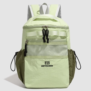 Detail of light green nylon backpack featuring front mesh pocket and brand logo