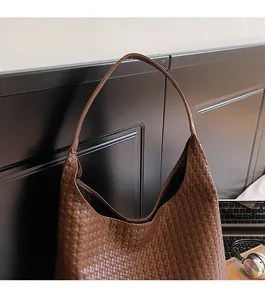 Detail of deep brown woven texture on a soft Hobo bag hanging in a workplace setting