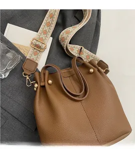 Sac seau marron avec bandoulière rétro posé sur un blazer gris élégant et chic