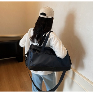Sac de voyage sport bleu foncé porté en bandoulière dans un décor de maison moderne