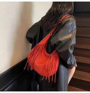 Detailed view of red suede hobo bag with fringe on model in black leather coat