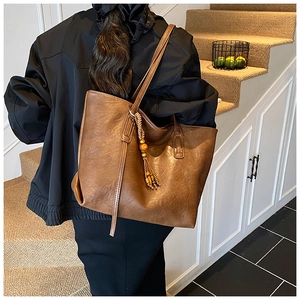 Dettaglio della borsa tote marrone vintage con ciondolo di perline e nappa decorativa