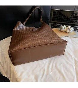 Detailed view of brown woven tote bag next to laptop and headphones on a desk