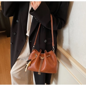 Caramel bucket bag detail showing drawstring closure and colorful wooden bead tassels