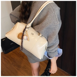 Detail of cream white leather shoulder bag with chic baseball charm and metal logo