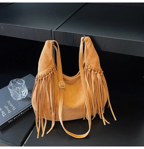Close-up of vintage brown suede tote bag featuring bohemian tassels and adjustable strap