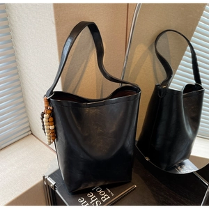 Detail of black faux leather bucket bag with three-color wooden bead charm decoration