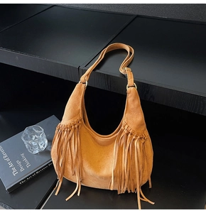 Detail of tan suede shoulder bag featuring long side tassels and bohemian retro styling