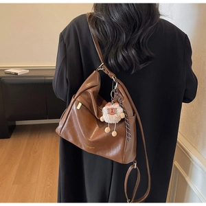 Detail of vintage brown leather hobo bag with gold logo and plush animal pendant