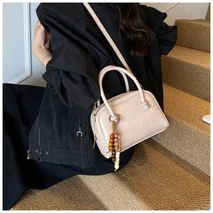 Chic beige leather bowling bag with bead tassel detail shown in a lifestyle setting