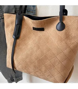 Detail of khaki suede tote bag with quilted diamond pattern and black leather strap