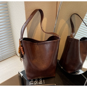 Close-up of deep brown tote bag with matte texture and ethnic beaded tassel detail