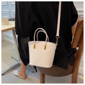 Close-up of white crocodile pattern bucket bag with golden hardware and luxury texture