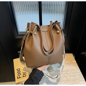 Détail du sac seau en cuir marron café avec bandoulière géométrique et perles métalliques
