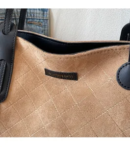 Close-up of brown quilted suede tote bag showing the gold FASHION & BAGS logo patch