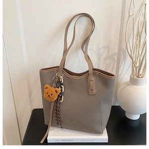Detail of lychee textured leather tote bag in coffee grey with a cute bear charm