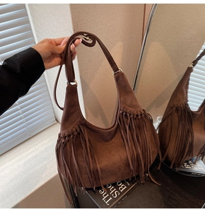 Detail of brown suede hobo bag featuring bohemian fringe and adjustable shoulder strap