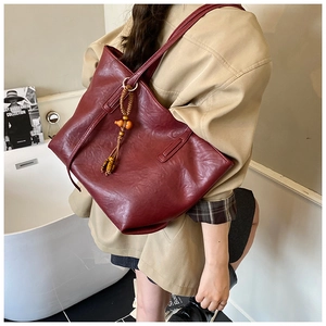 Modella che indossa una borsa tote bordeaux minimalista con nappa di perline elegante