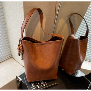 Detail of vintage brown bucket bag with bead pendant and realistic leather texture