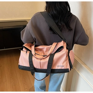 Vue détaillée du sac de sport rose et noir avec bandoulière réglable sur parquet