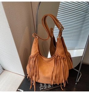 Detail of brown suede fringe tote bag with gold ring hardware and reflection in the mirror