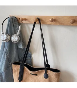 Detail of quilted brown suede tote bag with black leather straps hanging on a wooden hook