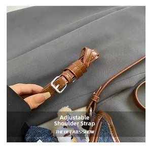 Detail of adjustable brown faux leather strap with silver buckle and fine stitching