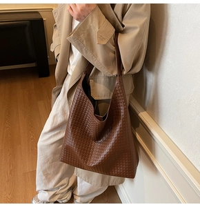 Close-up of the woven texture on this large dark brown leather tote bag with a wide strap