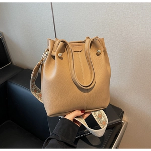 Détail du sac seau en cuir grainé avec une bandoulière tissée aux motifs géométriques