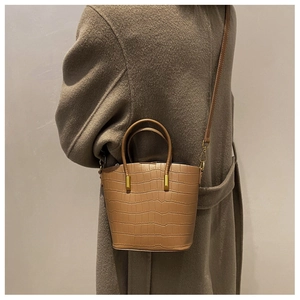 Brown crocodile embossed bucket bag styled with camel cashmere coat for a chic winter look