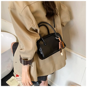 Détail d'un sac bowling chic en cuir noir avec perles colorées et bandoulière