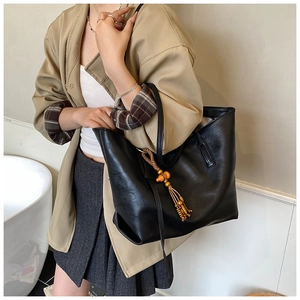 Dettaglio della borsa tote nera minimalista con nappa in perline di legno vintage e liscia
