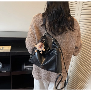 Rear view of a black soft PU hobo bag with cute bear charm in a cozy library setting